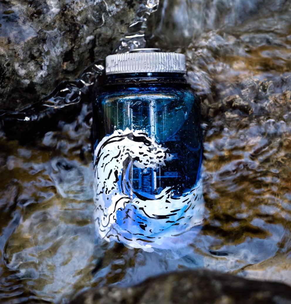 image of a nalgene water bottle sitting in a stream on some rocks