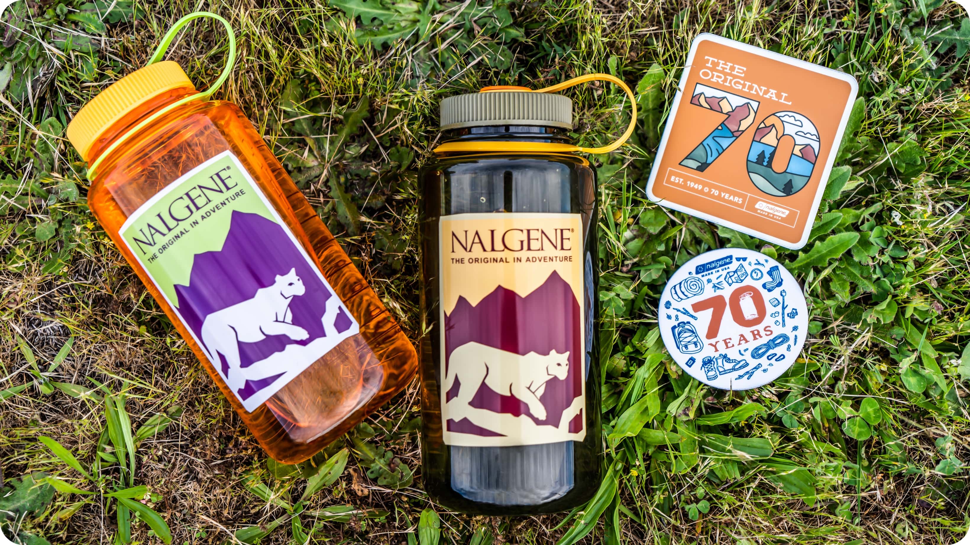 Nalgene water bottles laying in grass next to Nalgene stickers