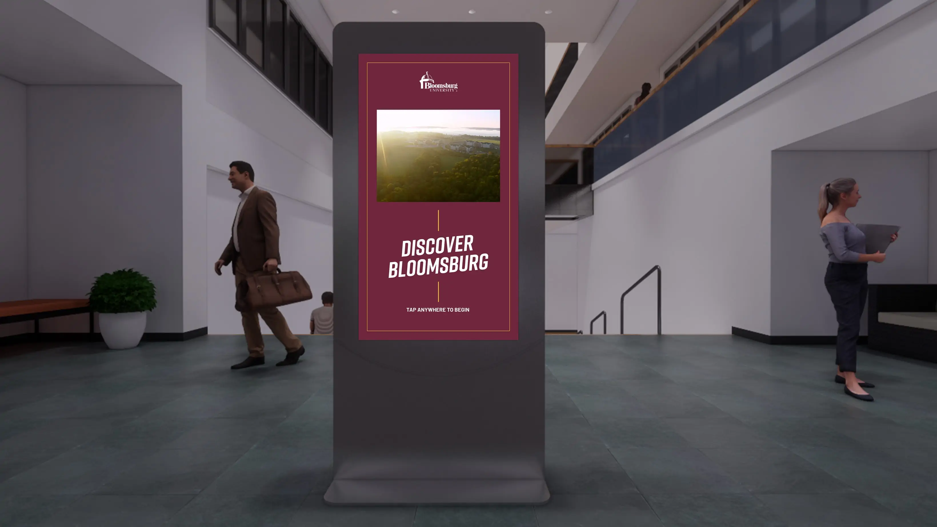 Image of a tall electronic display in the middle of a building by a stairwell with a "Discover Bloomsburg" Image on the screen
