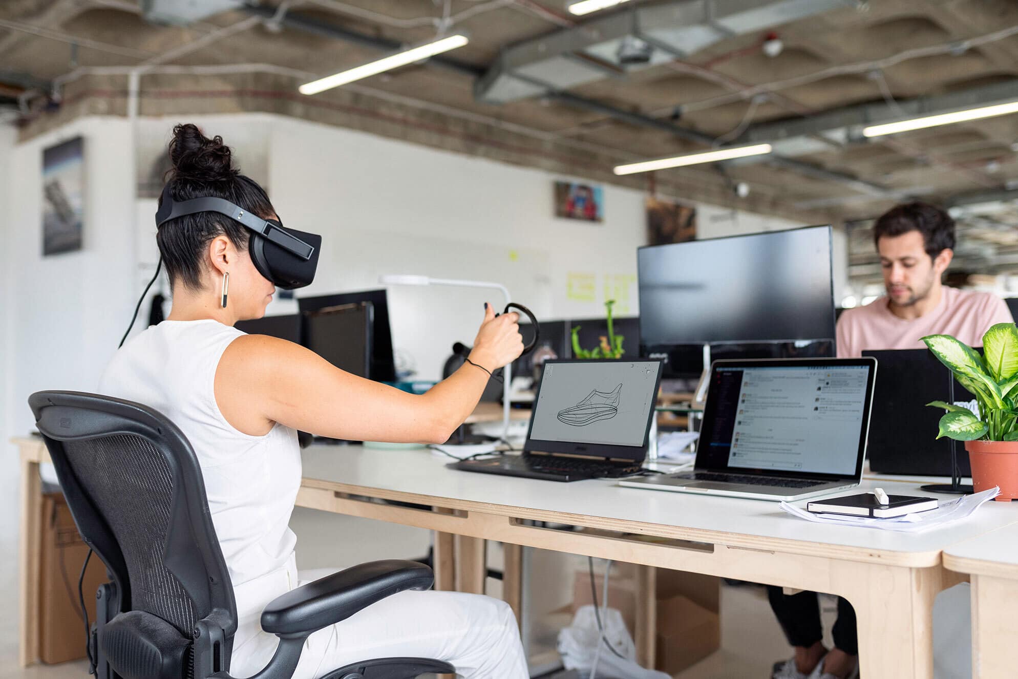 A female engineer sits at her desk wearing AR goggles.